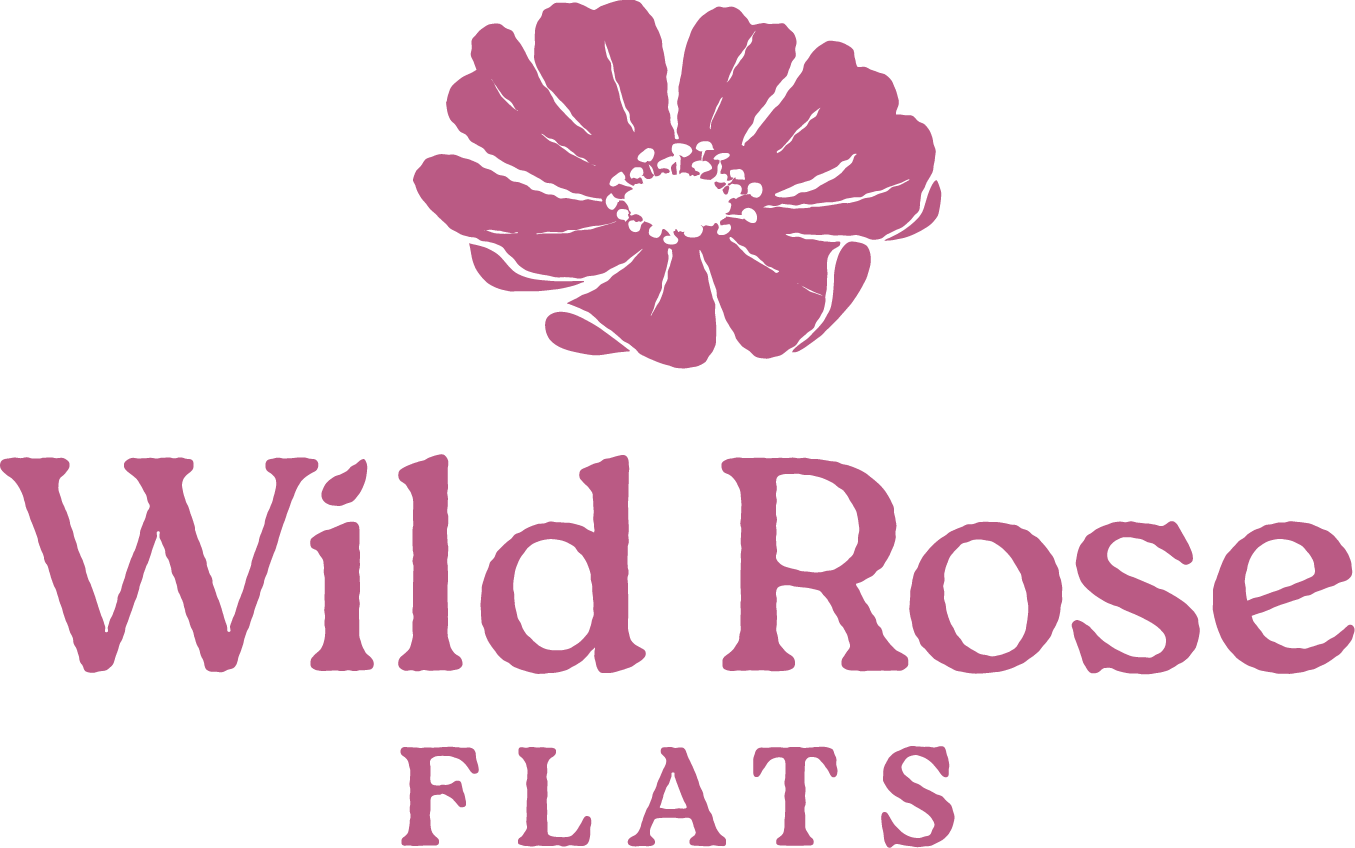A logo with a flower and the words "Wild Rose Flats".